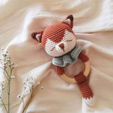 Sleepy fox baby rattle on cream blanket with branch